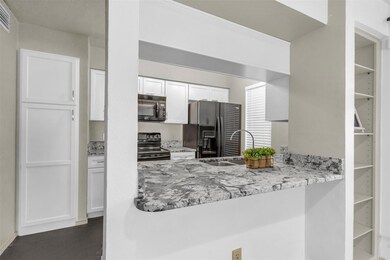 Kitchen with white cabinetry, a sink, black applia