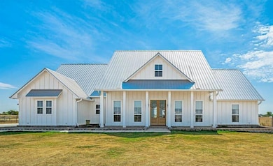 Modern farmhouse style home featuring board and batten siding, covered porch, a front lawn, and french doors