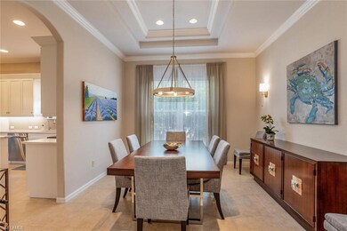 Formal Dining area featuring arched walkway to kitchen, molding, light tile patterned floors, a raised ceiling, and recessed lighting