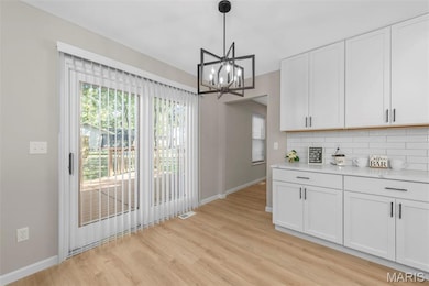 Unfurnished dining area featuring light wood-style floors, plenty of natural light, and a chandelier
