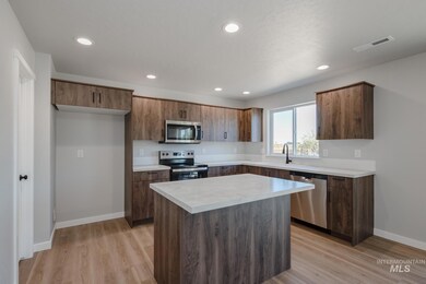 Kitchen featuring stainless steel appliances, a kitchen island, light countertops, light wood finished floors, and recessed lighting