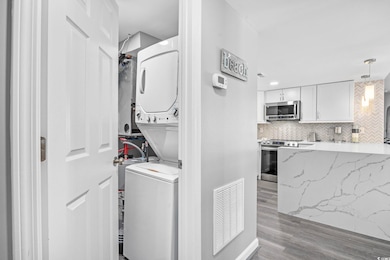 Laundry room featuring light wood finished floors and estacked washer and dryer