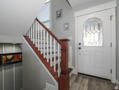 Foyer entrance with dark wood-style floors, stairway, and a textured ceiling