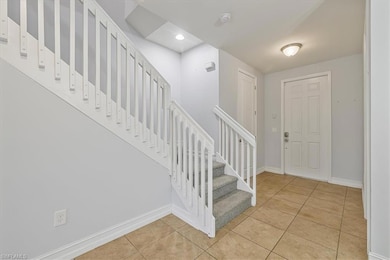 Foyer entrance with stairs, light tile patterned floors, baseboards, and recessed lighting