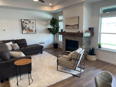 Living area with dark wood-type flooring, a stone fireplace, and recessed lighting