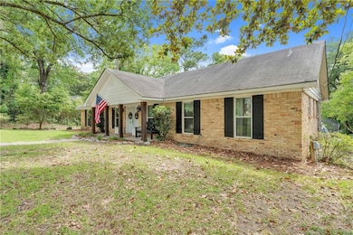 Ranch-style home with brick siding, a porch, a front yard, and roof with shingles