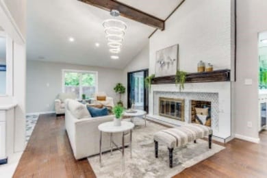 Living area with beamed ceiling, wood finished floors, a glass covered fireplace, and high vaulted ceiling