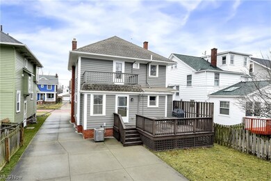 Back of house featuring a lawn, deck, and a balcony