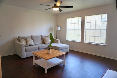 Living area with a ceiling fan and dark wood finished floors