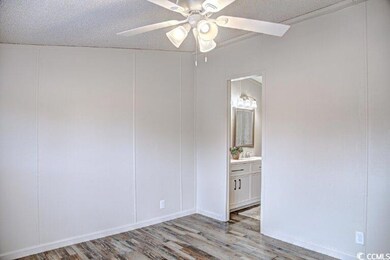 Empty room with ceiling fan, wood finished floors, a textured ceiling, and a decorative wall