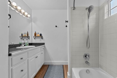 Bathroom featuring shower / tub combination, vanity, and dark wood-type flooring