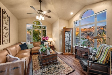 Living area featuring vaulted ceiling, dark wood-style flooring, and a ceiling fan