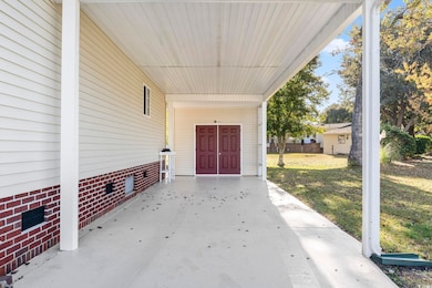 View of exterior entry featuring crawl space, a lawn, an attached carport, and a patio area