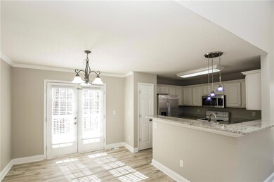 Kitchen featuring stainless steel appliances, a peninsula, light wood-style floors, baseboards, and crown molding