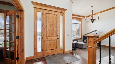 Foyer featuring crown molding, hardwood / wood-style floors, a chandelier, baseboards, and visible vents