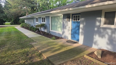 Doorway to property featuring a deck, a lawn, brick siding, a shingled roof, and a chimney