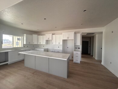 Kitchen featuring white cabinets, a kitchen island, light wood finished floors, a textured ceiling, and light stone countertops