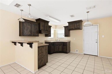 Kitchen featuring a breakfast bar area, light tile patterned floors, visible vents, a sink, and dark brown cabinetry