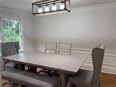 Dining room featuring ornamental molding, wood finished floors, a wainscoted wall, and a decorative wall