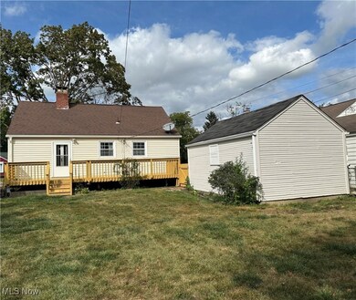 Rear view of property featuring a lawn, a deck, an outbuilding, and a chimney