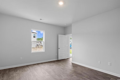 Empty room with dark wood-style flooring, visible 