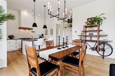 Dining room with light wood-style floors, a chandelier, recessed lighting, and a high ceiling