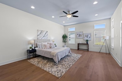 Bedroom with wood-type flooring, a ceiling fan, b