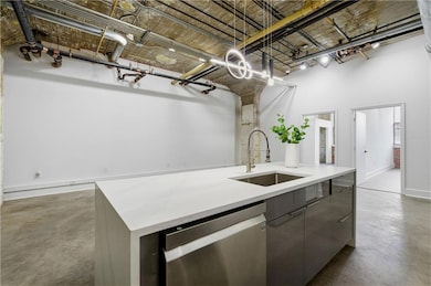 Kitchen featuring concrete flooring, an island with sink, dishwasher, light stone countertops, and modern cabinets