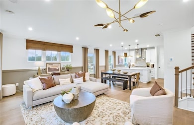 Living room with stairway, a chandelier, light wood-style flooring, and recessed lighting