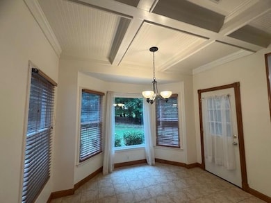 Unfurnished dining area with coffered ceiling, a chandelier, baseboards, crown molding, and beamed ceiling