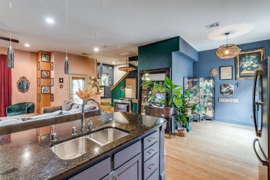 Kitchen featuring open floor plan, freestanding refrigerator, light wood finished floors, pendant lighting, and dark stone counters