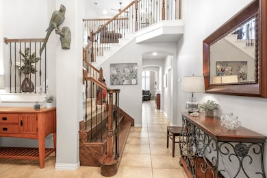 Foyer entrance with title flooring. The wide entry way with a views into the living room. To the left is the Formal Dining Room. Wood and rod Iron staircase with wide steps and landing areas.