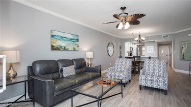 Living area with ornamental molding, wood tiled floors, ceiling fan, and a chandelier