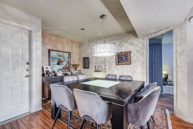 Dining area featuring dark wood-style flooring, a chandelier, and a textured ceiling