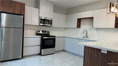 Kitchen with sink, appliances with stainless steel finishes, backsplash, and decorative light fixtures