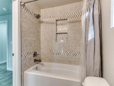 Full bath featuring shower / tub combo and wood finished floors