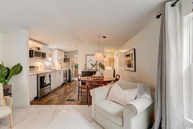 Living area featuring dark wood-type flooring, washer / clothes dryer, and vaulted ceiling