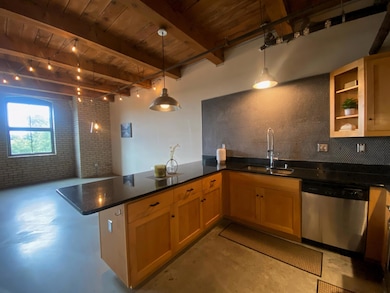 The open kitchen features a large peninsula that can accommodate seating on two sides. The industrial accent light package compliments the rich, heavy timber framing and exposed brick.