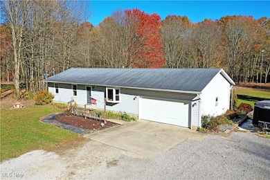 Ranch-style house featuring driveway, a wooded view, a front lawn, and a garage