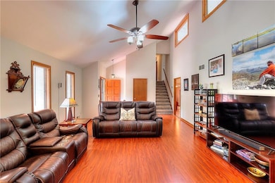 Living area featuring stairs, wood finished floors, high vaulted ceiling, and ceiling fan
