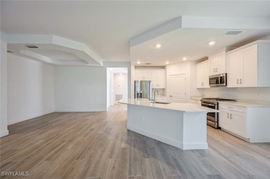 Kitchen with a sink, white cabinetry, light wood f
