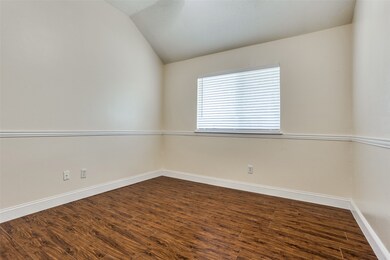 Empty room with lofted ceiling, dark wood-type flooring, and baseboards