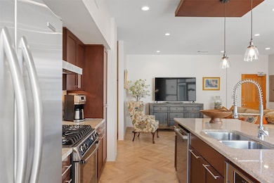 Kitchen with appliances with stainless steel finishes, light stone counters, pendant lighting, recessed lighting, and under cabinet range hood