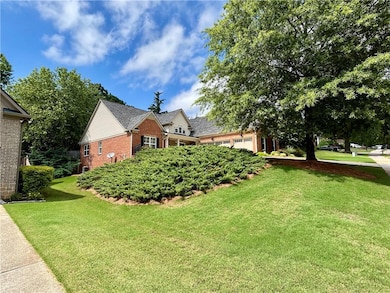 View of side of property with brick siding, a lawn, and a garage