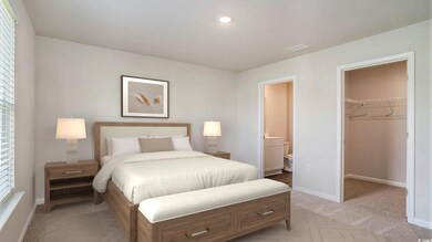 Virtually staged Bedroom featuring a spacious closet, light carpet, a closet, and ensuite bath