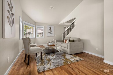 Living room with wood finished floors, lofted ceiling, and stairs