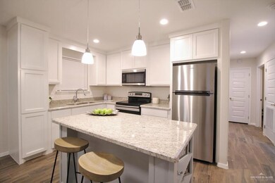 Kitchen featuring stainless steel appliances, a sink, dark wood-style floors, white cabinetry, and a center island