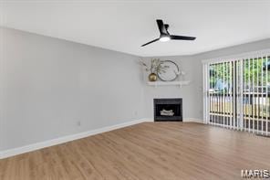 Unfurnished living room with wood finished floors, a fireplace, and a ceiling fan