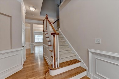 Staircase featuring wood finished floors, a decorative wall, and a wainscoted wall