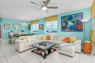 Living room with a chandelier, a ceiling fan, light tile patterned flooring, and a textured ceiling